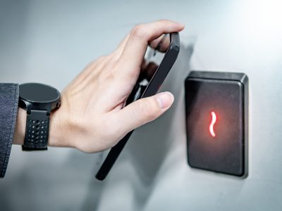 Using smarphone for door sensor scanning Male hand using smartphone for sensor scanning. Infrared sensor technology for automatic door access and security.